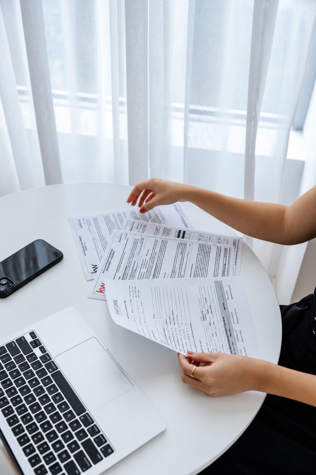 Reviewing real estate paperwork beside a laptop in a bright workspace